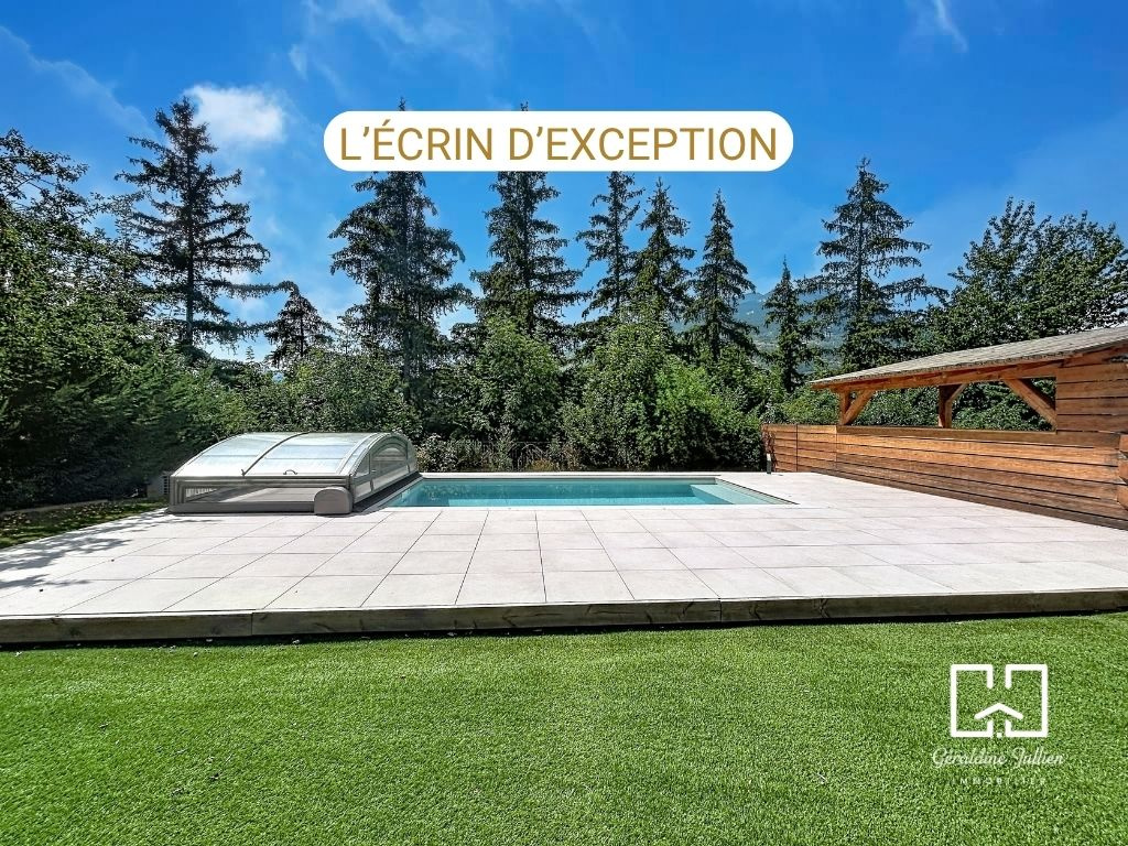 Maison avec piscine à Briançon Maison avec piscine et terrasse en bois, entourée d'arbres à Briançon.