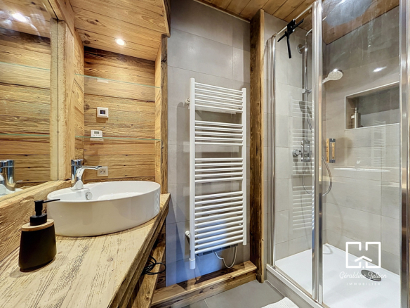 Salle de bain moderne avec douche et lavabo en bois, rénovée avec des matériaux de qualité.