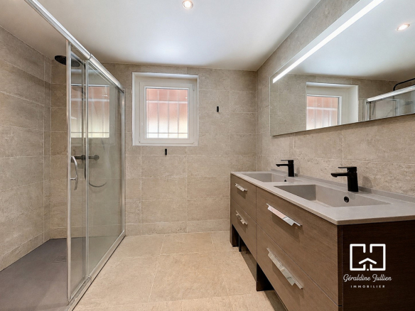Salle de bain moderne avec douche et double vasque, rénovée récemment.