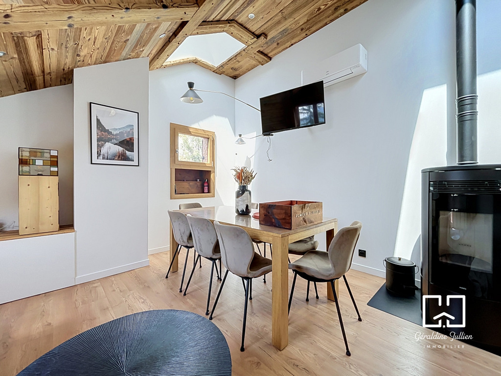 Intérieur d’une maison à Briançon Intérieur d'une maison rénovée avec une table à manger et un poêle à bois.