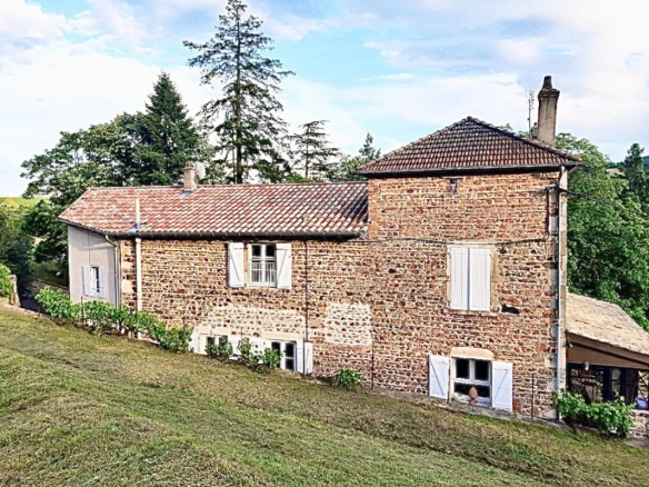 Maison en pierre rénovée à Beaujeu, entourée de verdure, avec un terrain arboré.