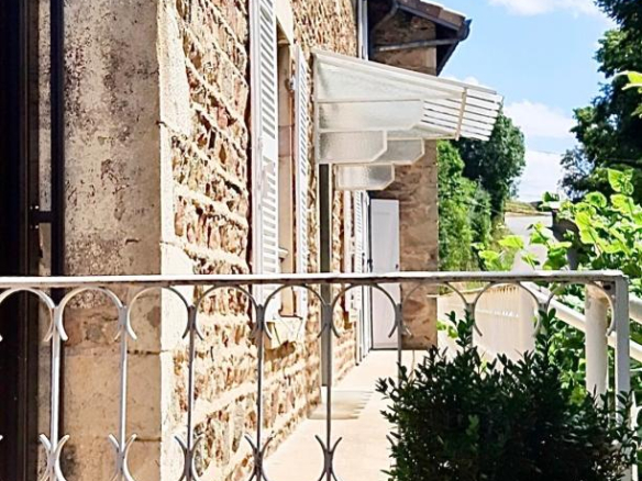 Façade d'une maison en pierre rénovée avec balustrade et volets à Beaujeu, Beaujolais.