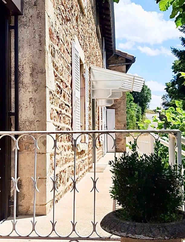 Façade d'une maison en pierre rénovée avec balustrade et volets à Beaujeu, Beaujolais.