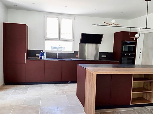 Cuisine moderne et spacieuse d'une maison rénovée à Beaujeu, avec des meubles en bois et des appareils électroménagers intégrés.