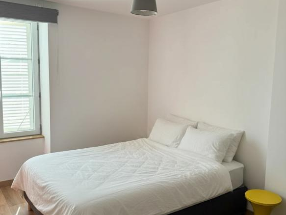 Chambre avec lit double et table de chevet jaune dans une maison à Ville-sur-Jarnioux.
