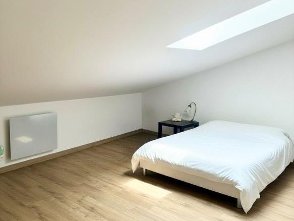 Chambre spacieuse avec lit et lumière naturelle, parquet en bois, dans une maison à Ville-sur-Jarnioux.