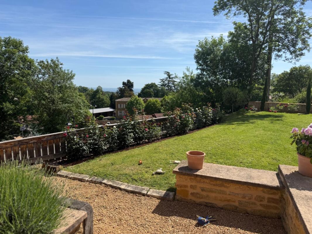Jardin à Ville-sur-Jarnioux Vue d'un jardin avec des rosiers et une terrasse en pierre à Ville-sur-Jarnioux.