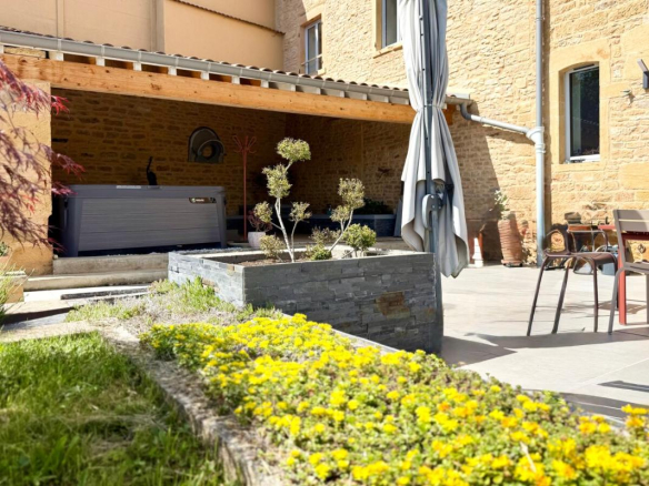 Terrasse avec jacuzzi et aménagement paysager devant une maison en pierre à Ville-sur-Jarnioux.