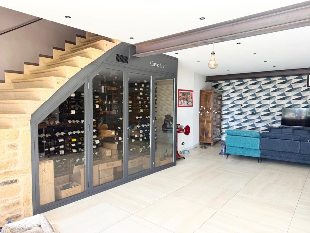 Intérieur d’une maison à Ville-sur-Jarnioux Intérieur d'une maison avec cave à vin, salon et escalier en pierre.