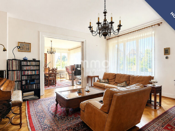 Intérieur d'une maison bourgeoise avec un salon lumineux, mobilier ancien et tapis au sol.