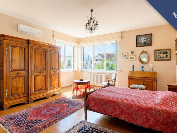 Chambre d'une maison bourgeoise à Barr, avec lit, armoire en bois et vue sur l'extérieur.