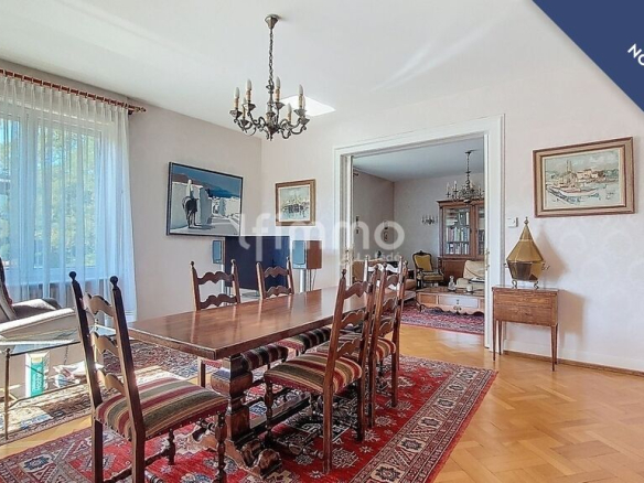 Salle à manger lumineuse avec table en bois et chaises, décorée de tapis et de tableaux.