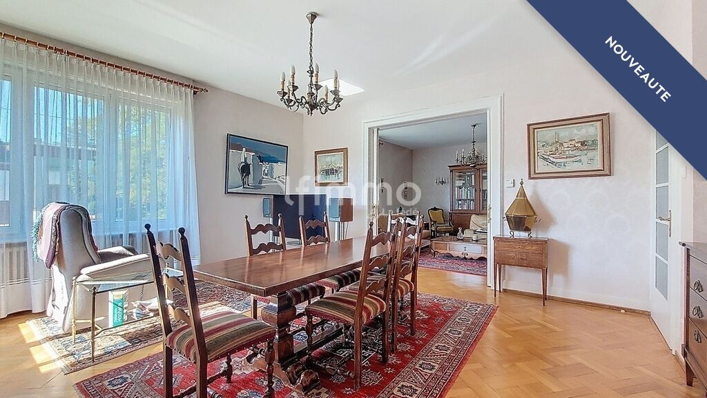 Salle à manger d’une maison bourgeoise à Barr Salle à manger lumineuse avec table en bois et chaises, décorée de tapis et de tableaux.