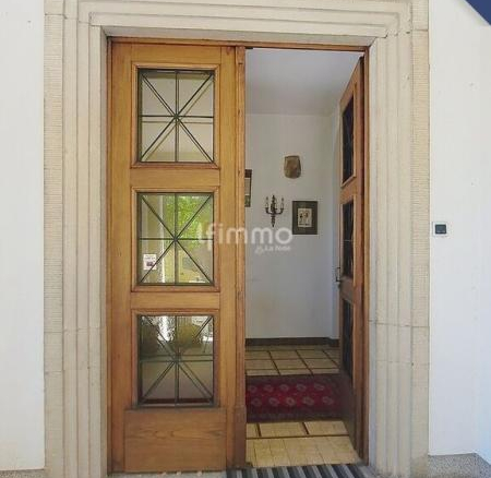 Entrée d'une maison bourgeoise avec porte en bois et tapis rouge.