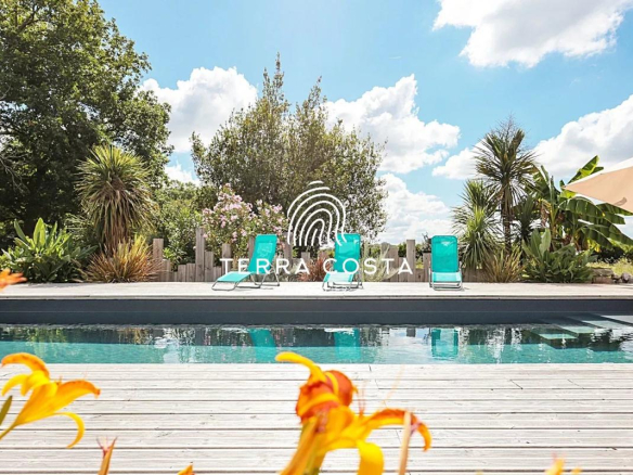 Vue de la piscine entourée de fleurs et de chaises longues dans un parc de 4 hectares.