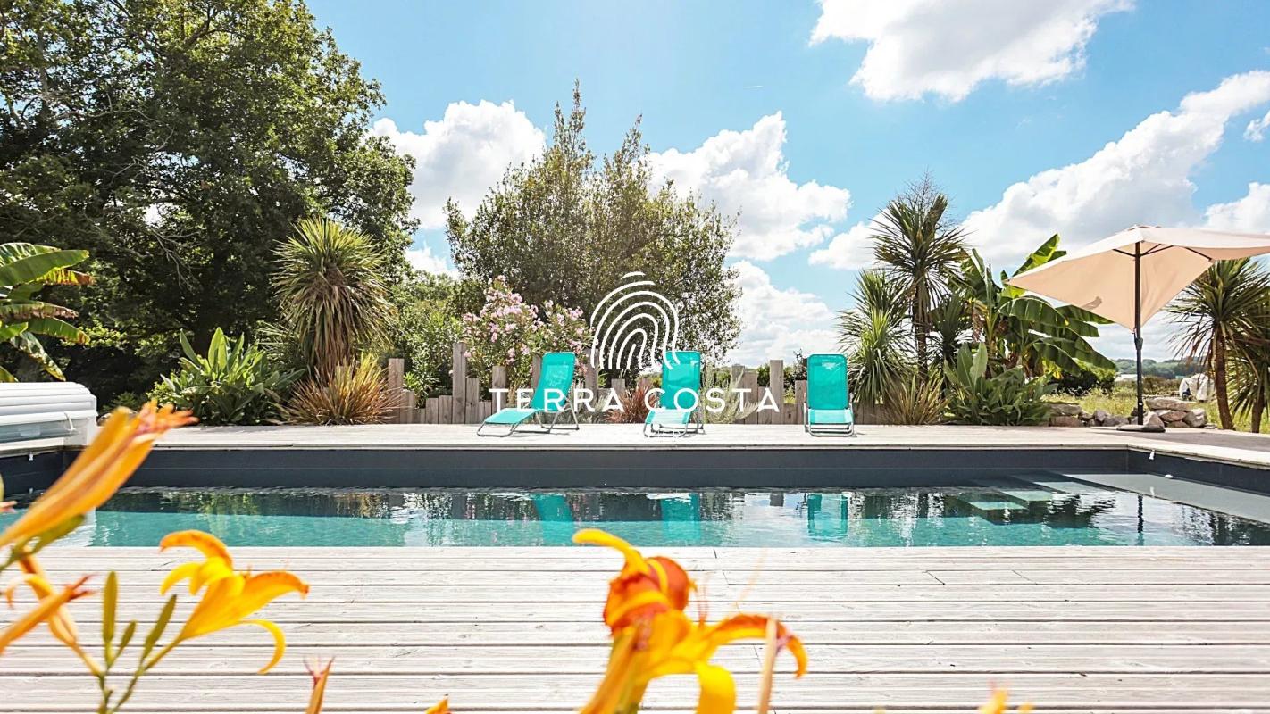 Vue de la piscine entourée de fleurs et de chaises longues dans un parc de 4 hectares.