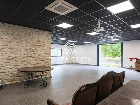 Intérieur d'un espace de réception avec murs en pierre et mobilier simple, Domaine de l'Anglade à Saint-Jean-de-Marsacq.