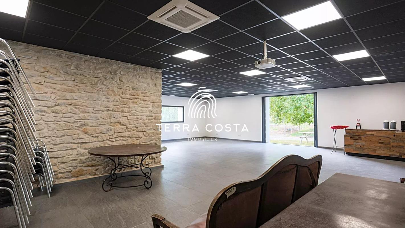 Intérieur d'un espace de réception avec murs en pierre et mobilier simple, Domaine de l'Anglade à Saint-Jean-de-Marsacq.