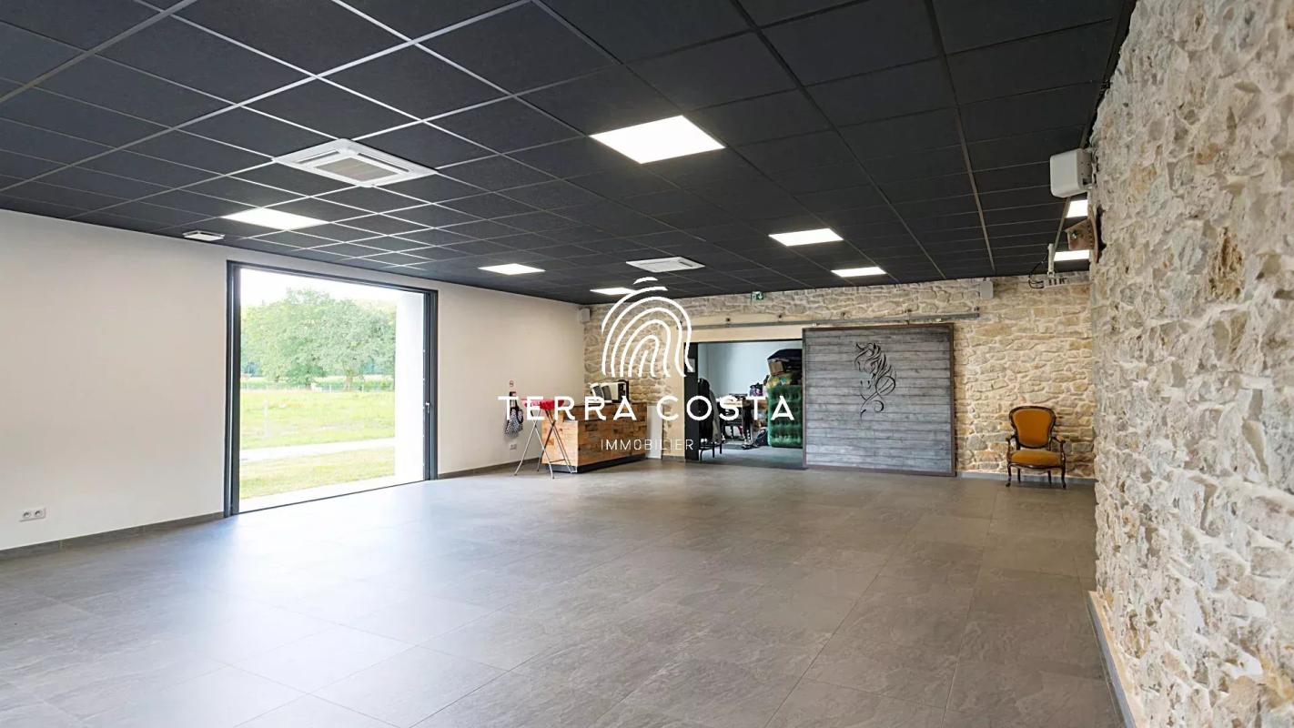 Intérieur d'un espace moderne avec des murs en pierre et un sol carrelé, ouvert sur un parc.