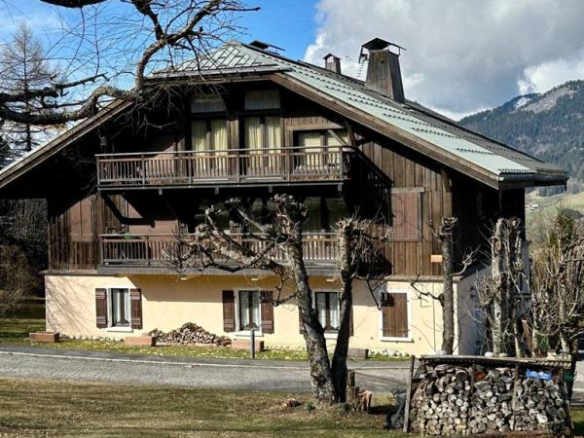 Chalet en duplex à Megève, entouré de verdure, avec balcons et cheminée.