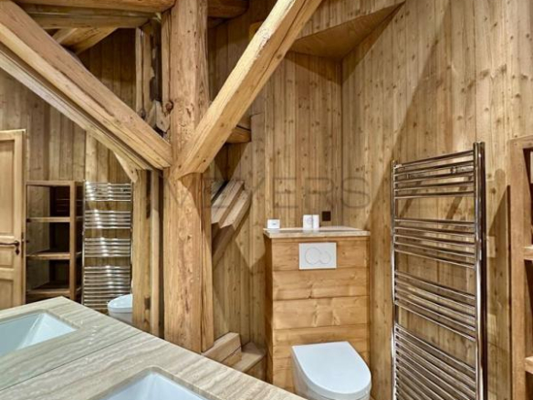 Salle de bain en bois avec baignoire et toilettes dans un chalet à Megève.
