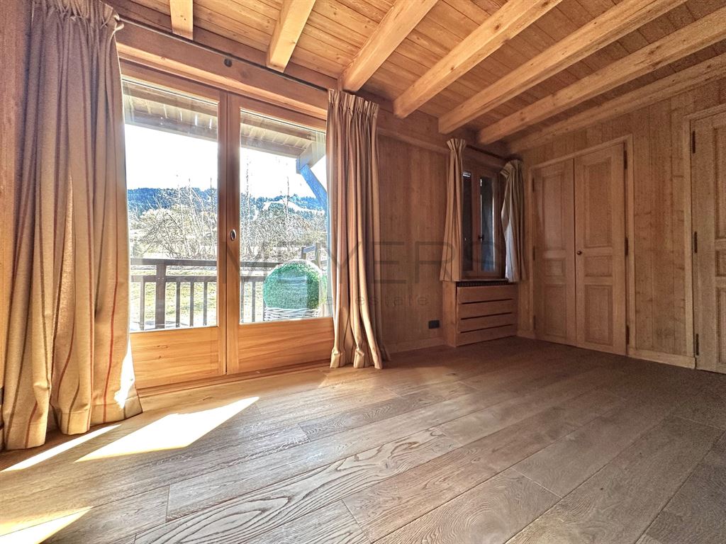 Intérieur d’un chalet à Megève Intérieur d'un chalet en bois avec lumière naturelle, fenêtres ouvertes sur un balcon.