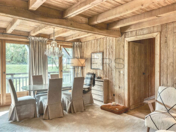 Intérieur d'un chalet à Megève avec salle à manger en bois et vue sur la nature.