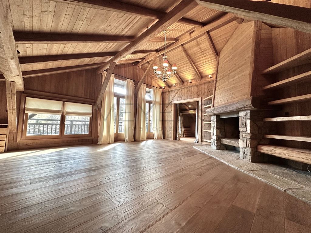 Intérieur d’un chalet à Megève Intérieur d'un chalet en bois avec cheminée, éclairage suspendu et grandes fenêtres à Megève.