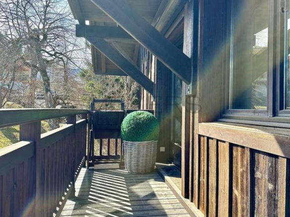 Balcon en bois d'un chalet à Megève avec un pot de fleurs rond.