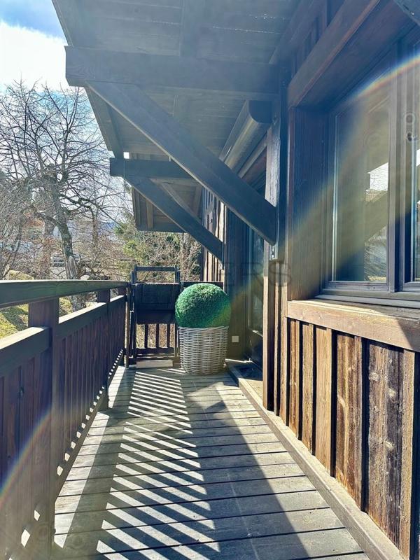Balcon d’un chalet à Megève Balcon en bois d'un chalet à Megève avec un pot de fleurs rond.