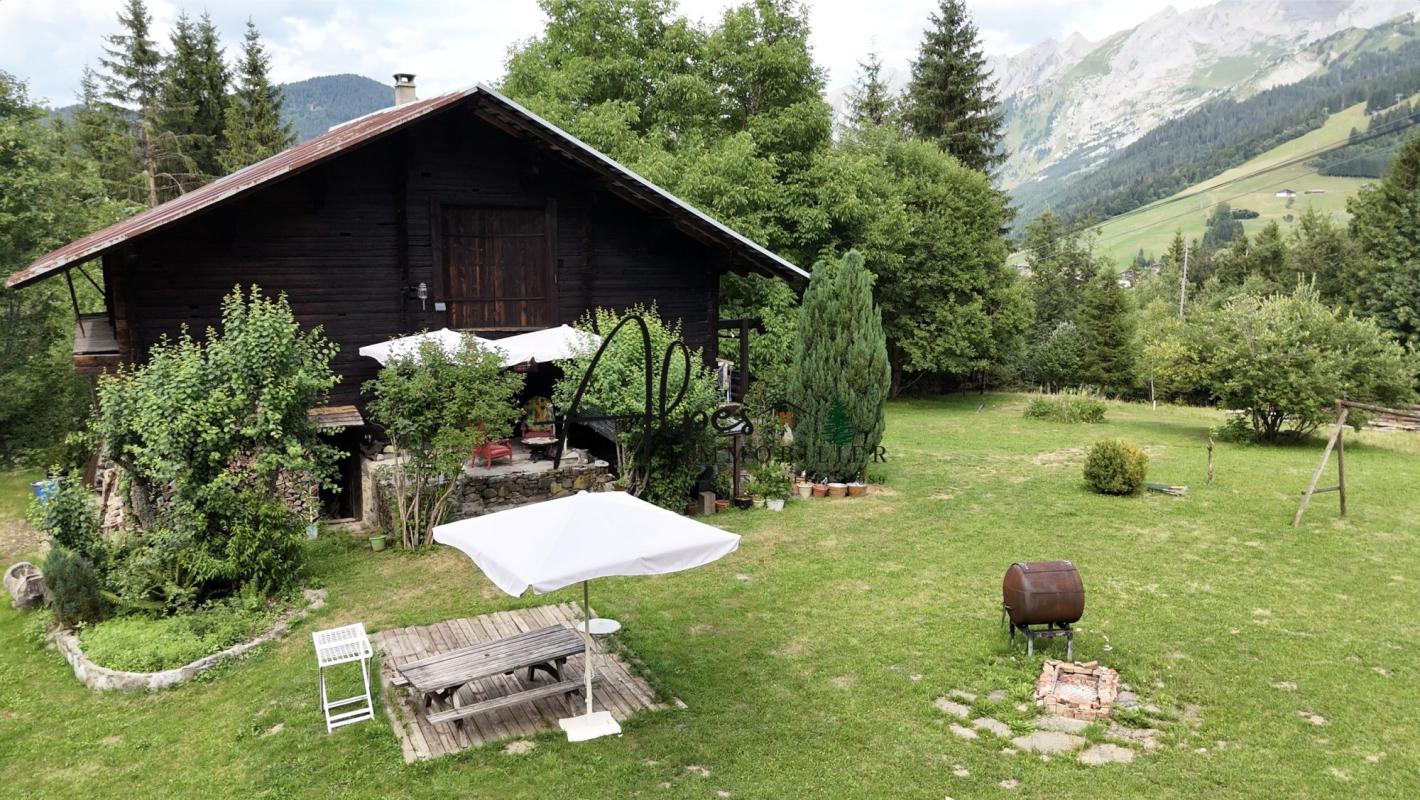 Authentique chalet d’alpage à La Clusaz Chalet d'alpage en bois entouré de verdure à La Clusaz, avec terrasse et jardin.