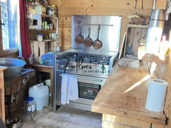 Intérieur d'un chalet d'alpage avec cuisine en bois et équipements de cuisine.