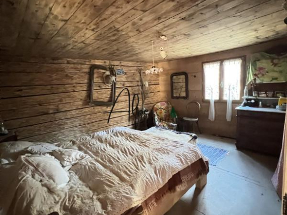 Intérieur d'un chalet d'alpage avec un lit en bois et des murs en bois, ambiance chaleureuse et rustique.