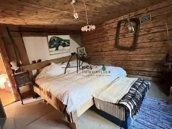 Chambre d'un chalet d'alpage avec lit en bois et décoration en bois naturel.