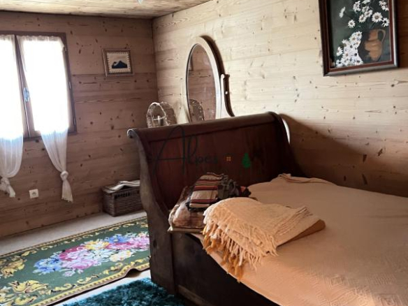 Chambre d'un chalet d'alpage avec un lit en bois et un tapis vert, décorée de manière authentique.