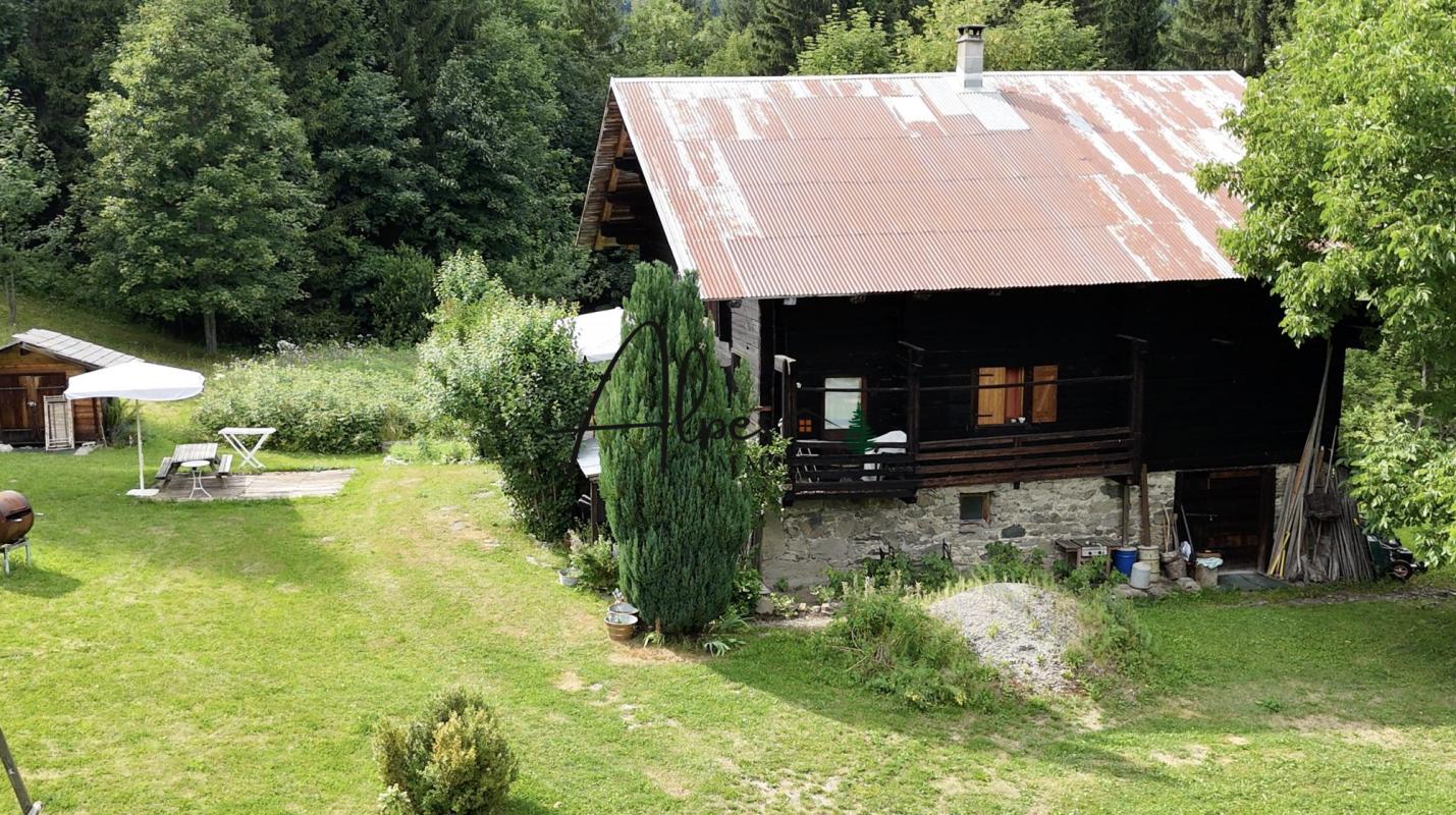 Chalet d’alpage à La Clusaz Chalet d'alpage en bois avec toiture en métal, entouré d'arbres et de verdure à La Clusaz.