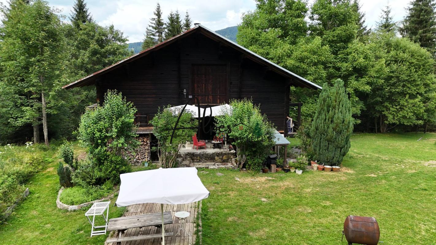 Chalet d’alpage à La Clusaz Chalet d'alpage en bois entouré d'arbres et d'un jardin verdoyant à La Clusaz.