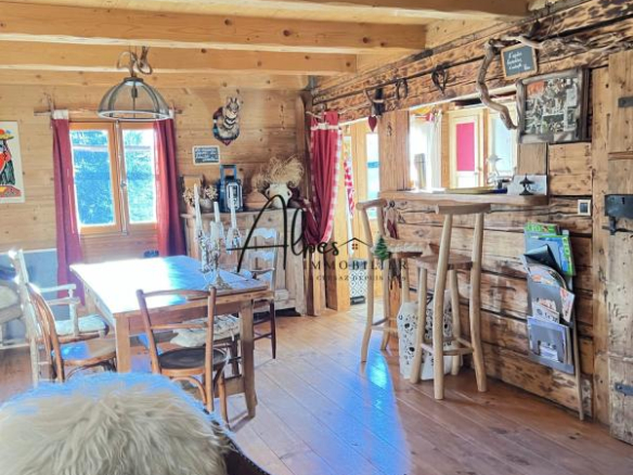 Intérieur d'un chalet en bois avec mobilier rustique, table en bois et décorations montagnardes.