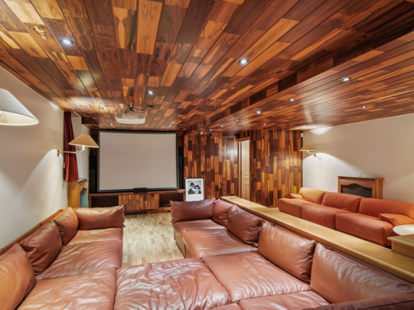 Intérieur d'une salle de cinéma avec un grand canapé en cuir et un écran de projection.