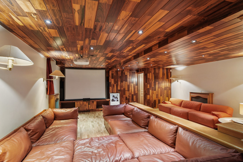 Salle de cinéma dans une propriété de prestige Intérieur d'une salle de cinéma avec un grand canapé en cuir et un écran de projection.