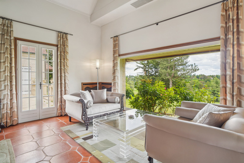 Salon d’une propriété de prestige au Golf de Saint-Nom-la-Bretèche Intérieur d'un salon lumineux avec canapés élégants et vue sur la verdure.