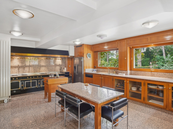 Cuisine spacieuse et moderne avec des meubles en bois et des fenêtres donnant sur la verdure.