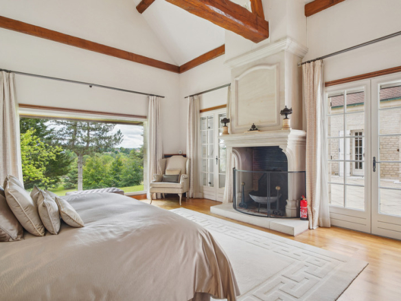 Chambre élégante avec cheminée et vue sur le jardin dans une propriété au Golf de Saint-Nom-la-Bretèche.