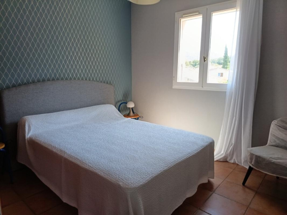 Chambre d'une maison à Toulon avec un lit double et une fenêtre laissant entrer la lumière.