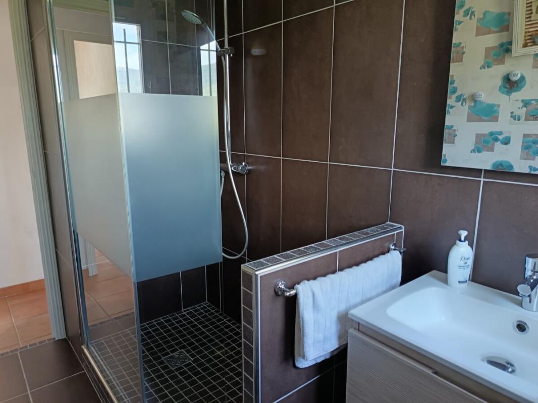 Salle de bain moderne Salle de bain moderne avec douche italienne et lavabo, carrelage foncé et murs clairs.