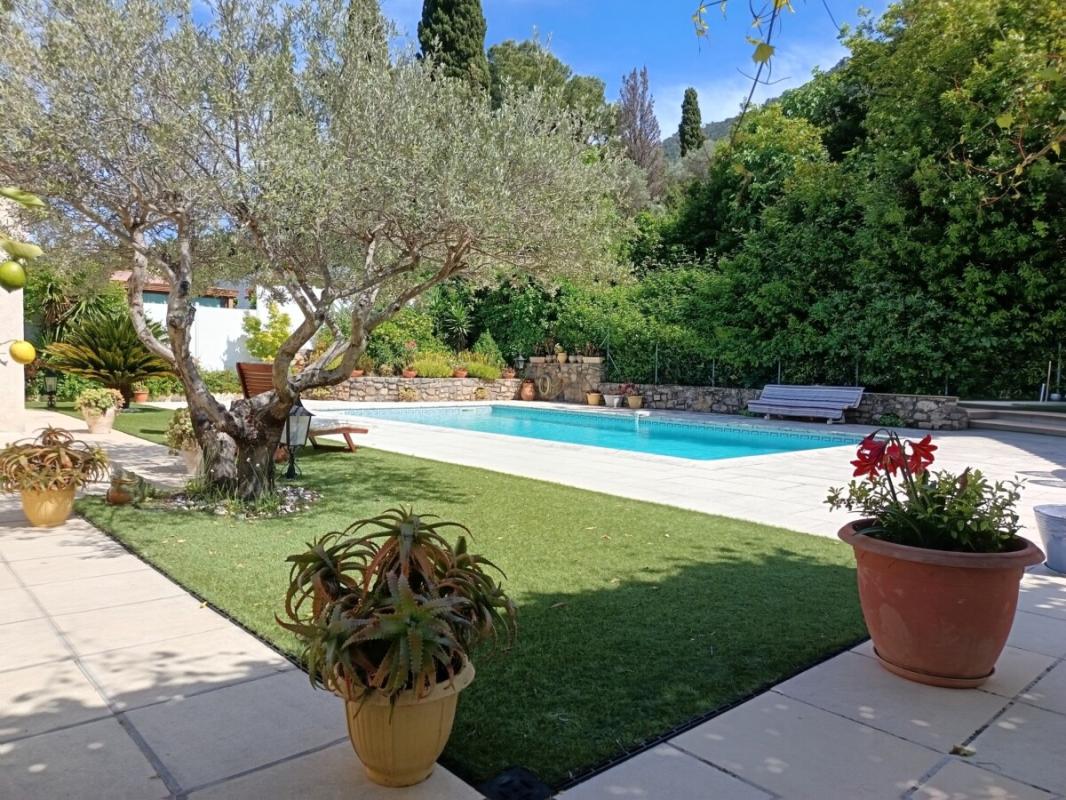 Jardin avec piscine à Toulon Vue d'un jardin avec piscine, arbres et plantes, devant une villa traditionnelle à Toulon.