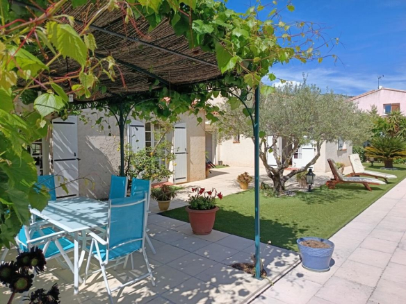 Terrasse d'une villa avec table et chaises, jardin et arbres, sous un treillis à Toulon.