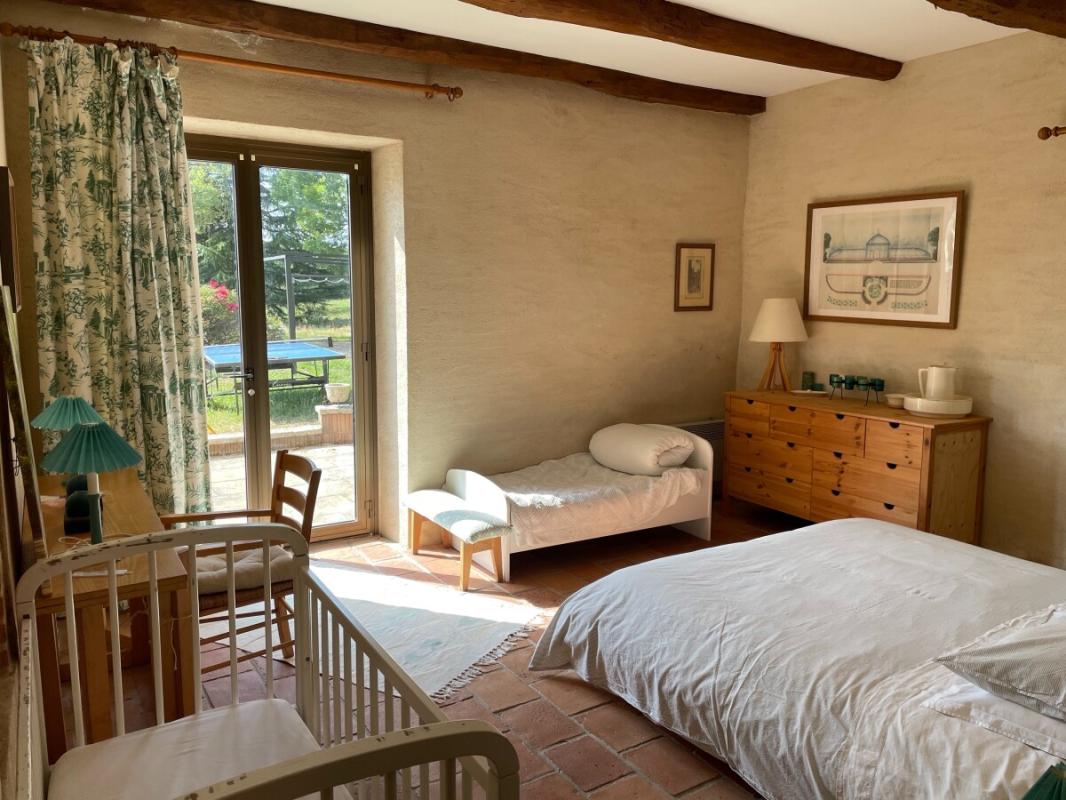 Chambre dans un corps de ferme rénové Chambre lumineuse avec lit, berceau et accès à l'extérieur dans un corps de ferme rénové.