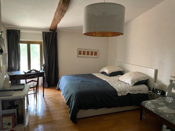 Chambre spacieuse avec lit double et bureau, décorée sobrement.