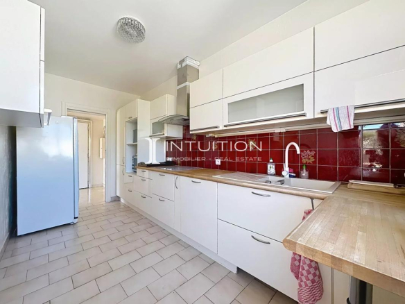 Modern and bright kitchen in an apartment in Cannes, with white furniture and light tiles.